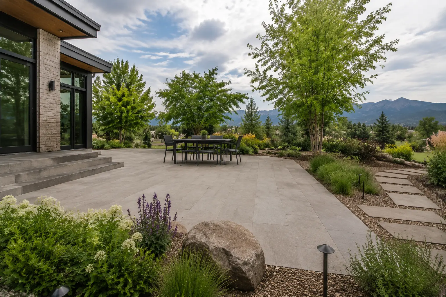 Completed large-format paver patio connecting the home, dining area, garden, and path